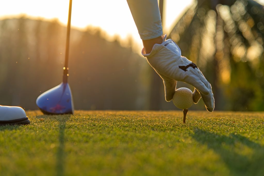 Hand asian woman putting golf ball on tee with club in golf cour