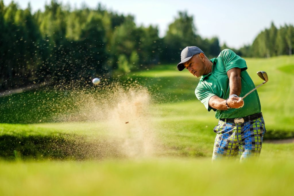 Golfer hits ball from a bunker with golf club