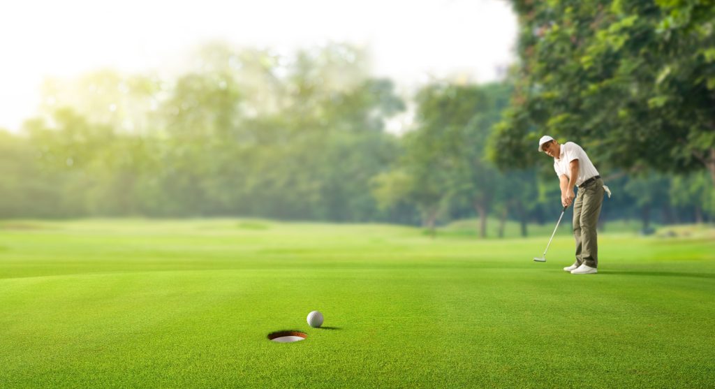 Golfer putting golf ball to the hole on green golf.