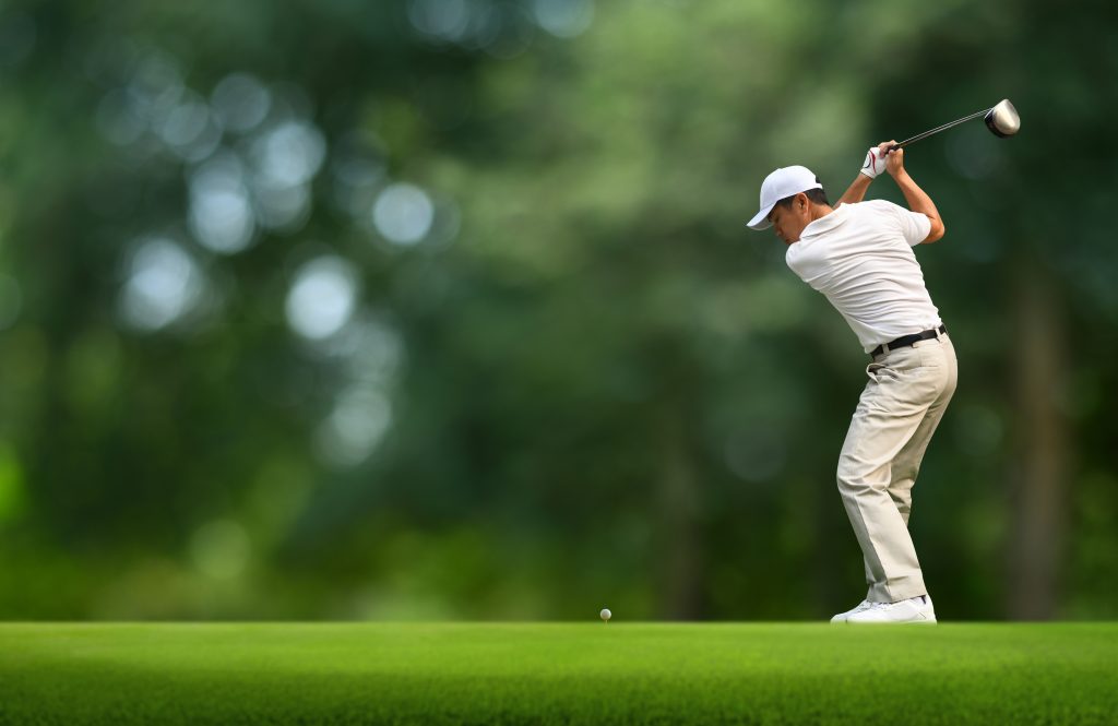 Front view of Golfer driver back swing before hitting golf ball down the fairway.