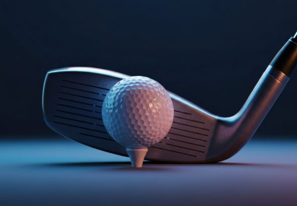 Close-up golf club poised to strike a white golf ball